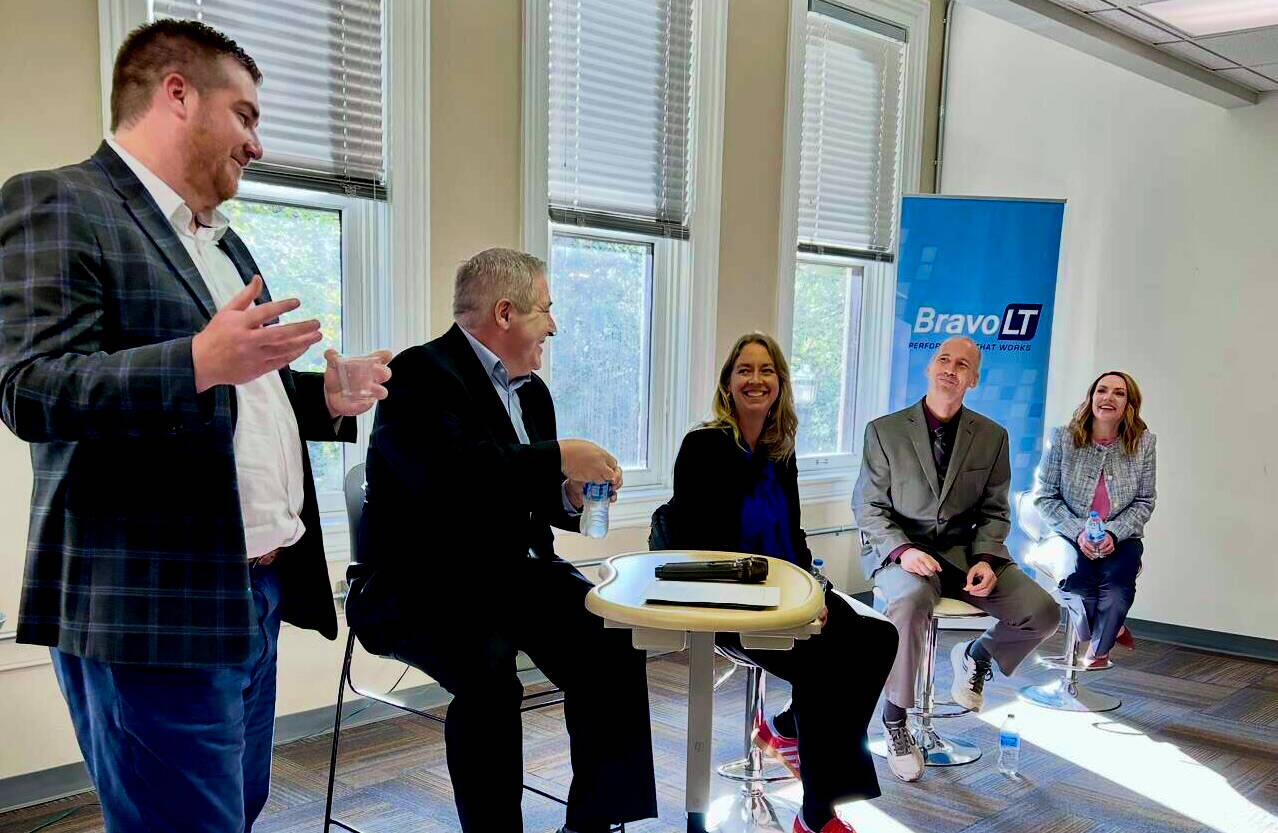 Panel discussion at a Tech Week Grand Rapids event hosted by Bravo LT. Five speakers sit at the front of the room, including GVSU College of Computing Assistant Dean Rachel Salinas (far right). The panelists are engaged in conversation.
